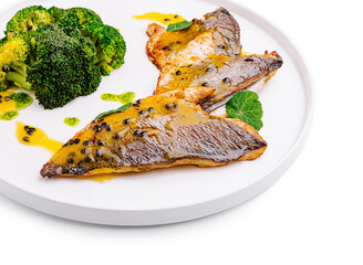 Freshly cooked fish with broccoli and sauce on a white plate