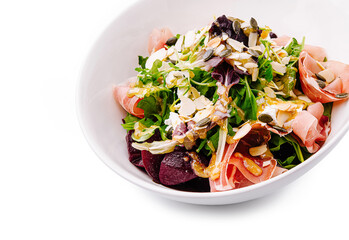 Fresh salad with greens, ham, and nuts served in a bowl