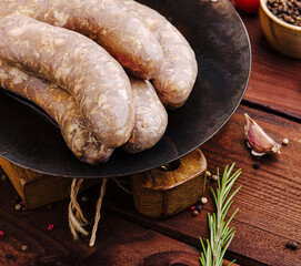 Juicy sausages on cast iron skillet with fresh herbs and spices