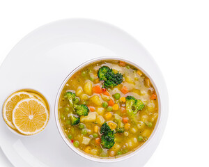 Colorful vegetable soup served with lemon slices on a white plate