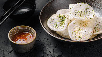 Crispy rice crackers served with spicy dipping sauce in a bowl
