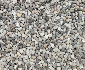 Texture of grey color of the crushed granite and limestone coarse gravel foreground closeup