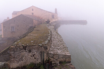 Ancient wool washing house in Los Barruecos, surrounded by fog.