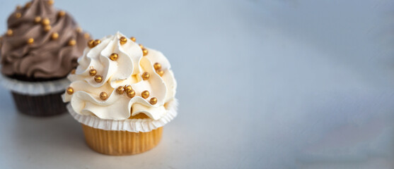 A duo of gourmet cupcakes with creamy frosting and golden decorations, minimal setting