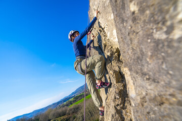 Young woman rock climbing on mountain cliff in nature