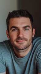 Obraz premium Caucasian young adult male with short hair and blue eyes in casual gray shirt smiling