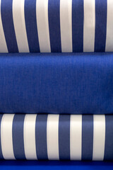 Fototapeta premium Colourful bolts of blue and white fabric cloth on a market stall for use as a background texture