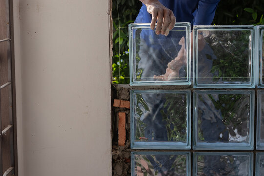 Focus to hand and finger of construction worker who a mason man working. Labors building glass brick block wall background. Selective focus and copy space.