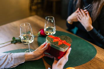Boyfriend gives his girlfriend a gift on a romantic dinner date in a restaurant.