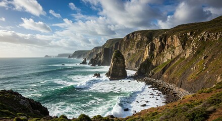 Obraz premium Towering cliffs meet the turquoise ocean as waves crash against rugged rock formations. The coastal landscape is bathed in sunlight, with a dramatic sky enhancing the wild, untamed scenery.