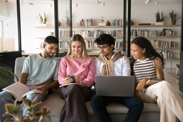 Four young, gen Z students using smartphone during break or recess in college library, watching funny, educational online content, share messages. Modern technology addiction, life habit, tech overuse
