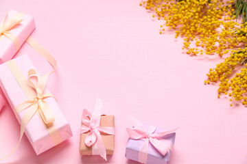 Composition with gift boxes and mimosa on pink background
