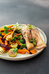 Baked silver carp with roasted carrots, zucchini, beets, and garlic , perfect for a healthy and delicious breakfast or lunch, plates with food on a dark background