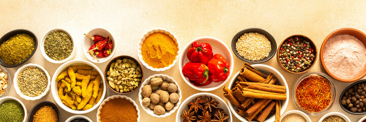 Collection of assorted spices and herbs spread on a beige background, blending exotic aromas and colors to inspire flavorful cooking, banner