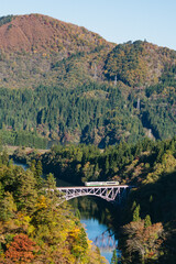 Fototapeta premium Fukushima, Japan-November 8,2024 : Bridge view of the mountain in autumn season with train