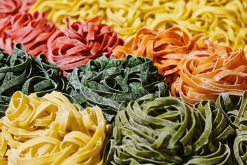 A vibrant display of fresh, colorful pasta nests in varying shades, creating an appetizing and artistic arrangement perfect for culinary and food-related themes.