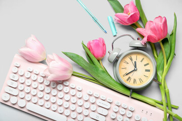 Alarm clock with tulip flowers and keyboard on white background © Pixel-Shot