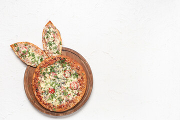 Board with tasty pizza with Easter bunny ears on white background