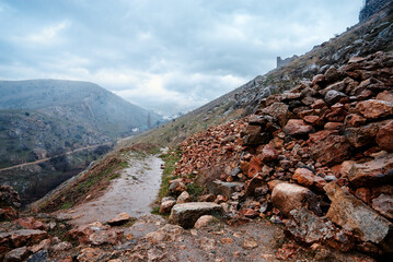 Rocky Landscape With Path and Cloudy Sky in Mountainous Terrain..