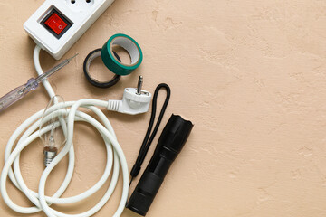Electrician's tools, extension cord and electronics on beige grunge background