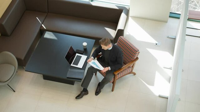 Upset disappointed stressed businessman checking documents with bad results. Man throwing papers away in the air - top down view