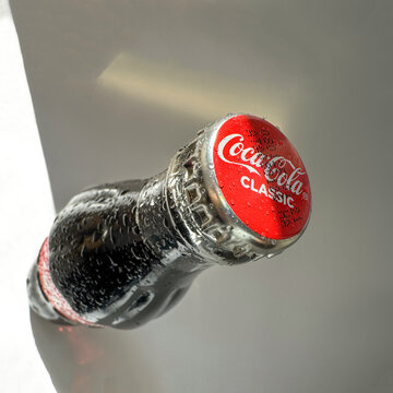 Coca Cola classic bottle and cap close up with ice on the background