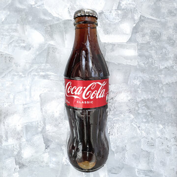 Coca Cola classic bottle and cap close up with ice on the background