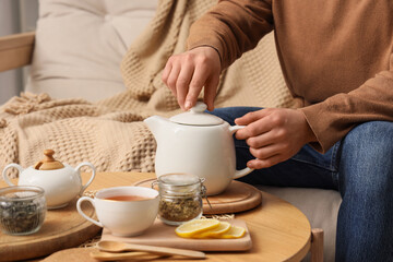 Young man brewing tea on table at home, closeup