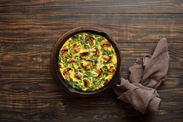 Frittata with spinach and champignon mushrooms in cast iron skillet