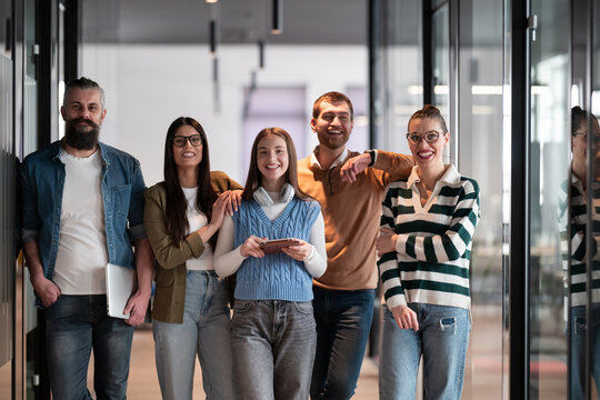 A diverse team of professionals in a modern coworking startup office smiles together, showcasing teamwork, collaboration, and a positive corporate culture that promotes innovation and a dynamic work