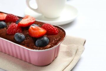 Delicious tiramisu cake with berries on table