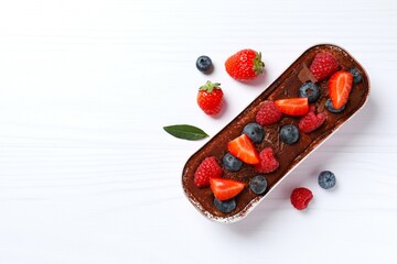 Delicious tiramisu cake with berries on table