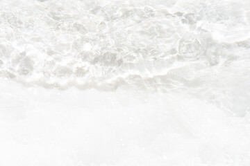 White water with ripples on the surface. Defocus blurred transparent white colored clear calm water surface texture with splashes and bubbles. Water waves with shining pattern texture background.