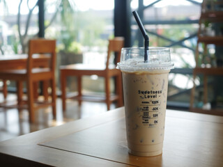 Iced Coffee in a Plastic Cup on a Wooden Cafe Table