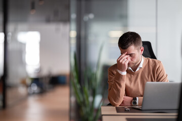 Businessman experiencing headache, fatigue, burnout, and stress in the office while working on a...