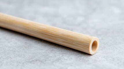 Naklejka premium Eco-friendly bamboo drinking straw lying diagonally on a grey textured stone surface in bright natural light.