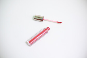 Red lip gloss in elegant glass bottle with shiny lid, container with brush isolated on white background, red lipstick