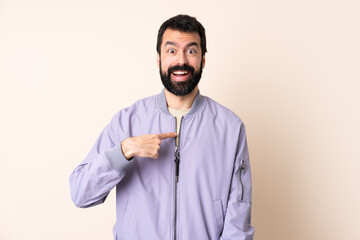 Obraz premium Caucasian man with beard wearing a jacket over isolated background with surprise facial expression