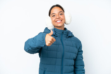 Young hispanic woman wearing a winter earmuffs isolated on white background with thumbs up because...