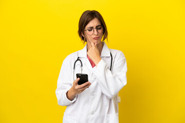 Doctor woman isolated on yellow background thinking and sending a message