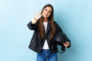 Obraz premium Young caucasian woman holding a motorcycle helmet isolated on blue background happy and counting four with fingers