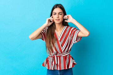 Young caucasian woman isolated on blue background frustrated and covering ears