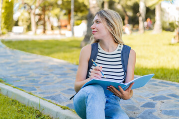 Obraz premium Young blonde woman at outdoors holding a notebook