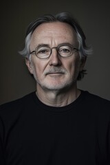 Obraz premium Thoughtful senior man with a gentle expression and distinguished features in moody lighting.