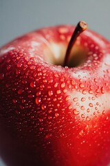 A juicy red apple with water droplets glistening on its surface, perfect for a still life or food related concept