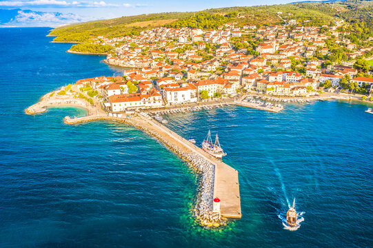 A stunning aerial view of Postira Riva on Brac Island, Croatia, captured on a summer afternoon, showcasing its charming waterfront, traditional stone buildings, and the crystal-clear Adriatic Sea