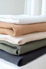 A stack of towels with different colors and textures. The towels are piled on top of each other, creating a visually interesting display. The variety of colors and textures adds depth