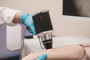 Closeup  doctor examines neoplasms or moles on the woman hand patient's skin - using special...