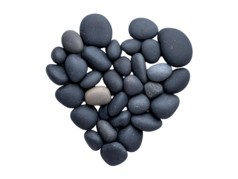 A heart shape created from smooth, dark pebbles symbolizes love and tranquility in nature.