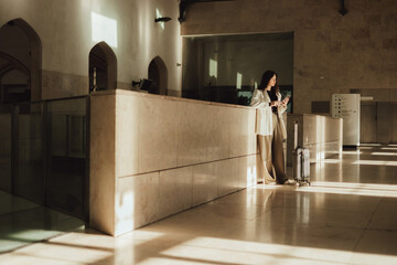 Vlogger traveler woman with suitcase using phone at train station in Lisbon. Business travel and...